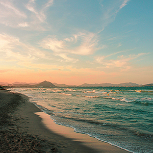 sea waves crashing on shore during sunset